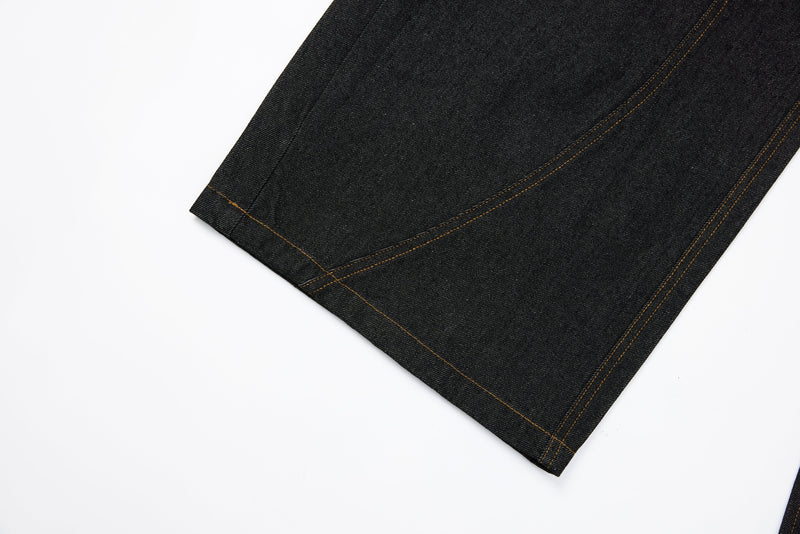 Hem close-up of dark wide-leg denim jeans with contrast stitching along the cuff