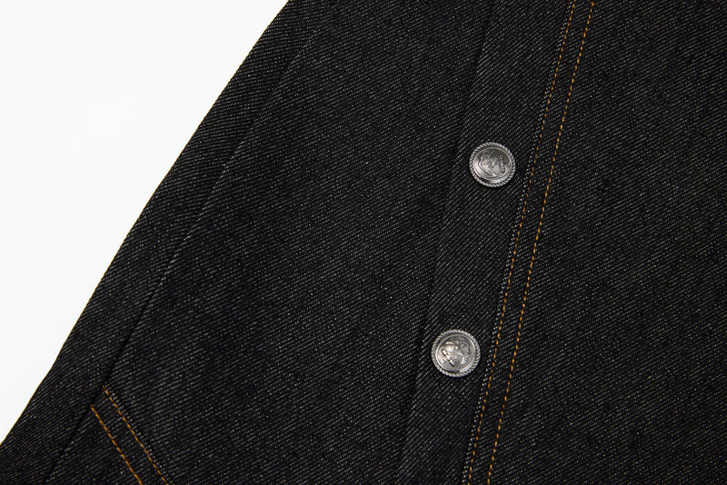 Close-up of dark denim panel seam with two silver snap buttons and tan topstitching