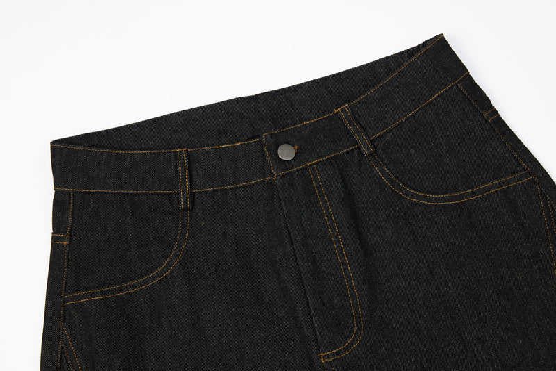 Close-up of the waistband and front pocket on dark denim jeans with a rivet panel detail