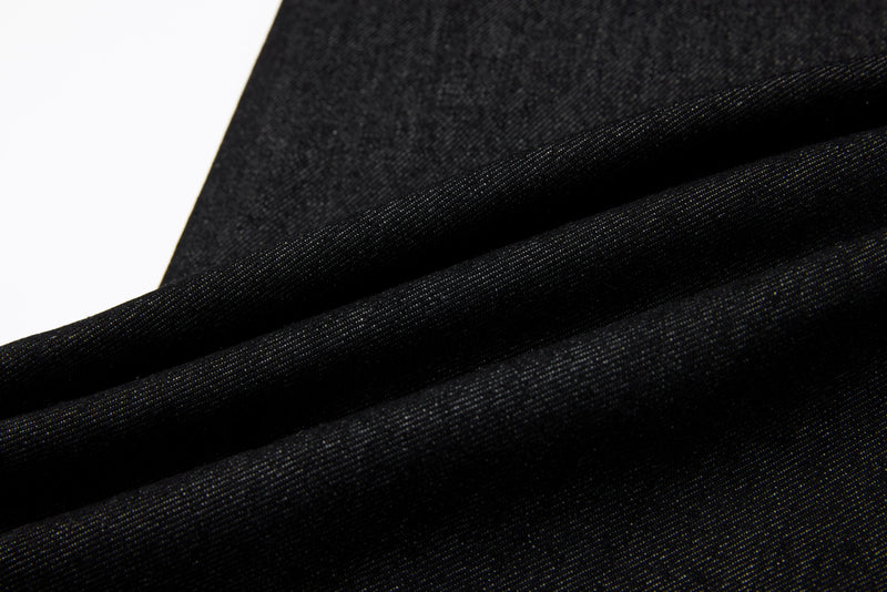 Close-up of dark denim fabric texture with soft folds and visible twill weave