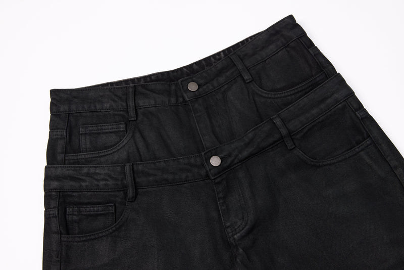 Close-up of stacked black jeans waistbands with buttons, belt loops, and front pockets