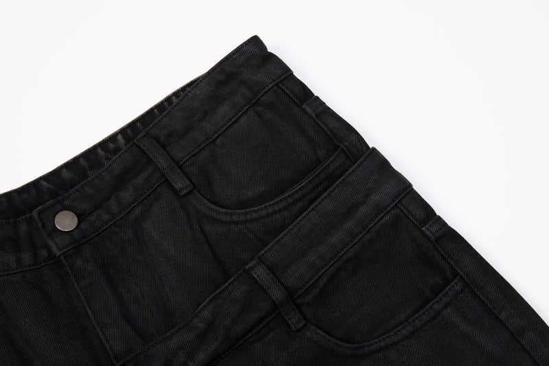 Close-up of black jeans waistband and curved front pocket on washed denim