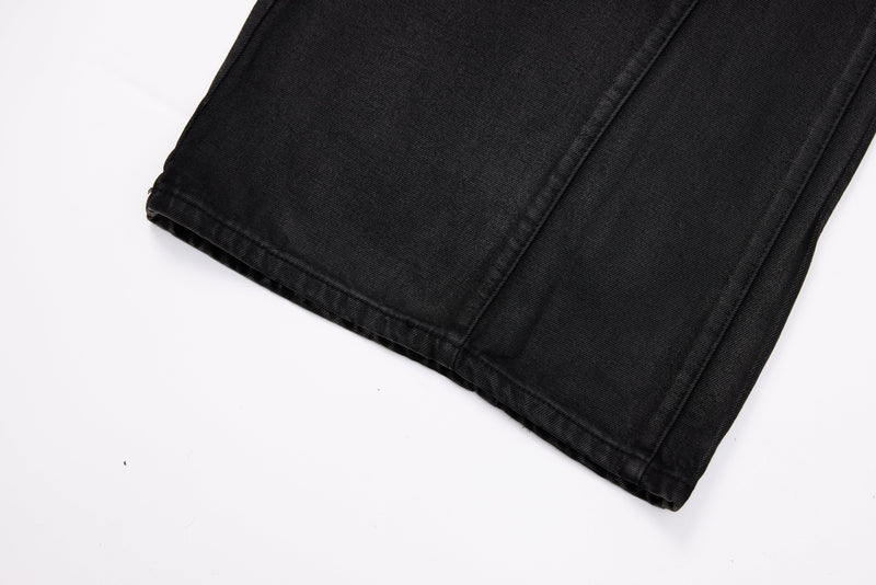 Close-up of black jeans hem showing straight wide-leg opening and stitched edge