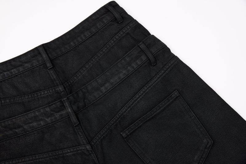 Close-up of black jeans back waistband and pocket stitching on washed denim