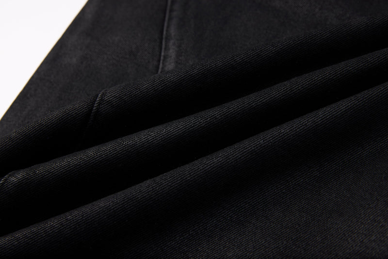 Close-up of black denim fabric folds showing the textured washed weave