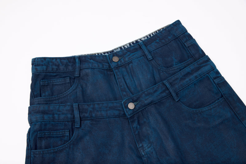 Close-up of layered double waistband and front pockets on dark blue washed jeans