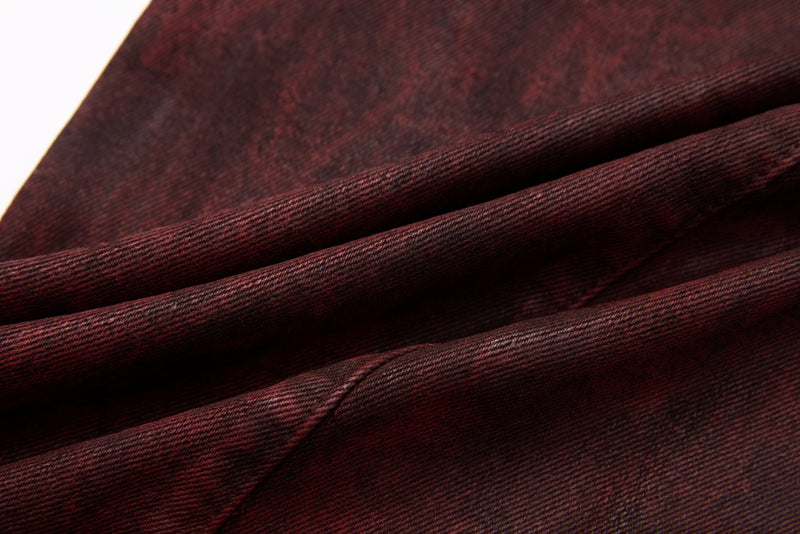 Close-up of burgundy denim fabric with soft diagonal folds and textured weave