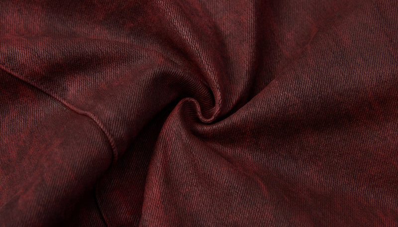 Close-up of burgundy denim fabric gathered into a spiral fold