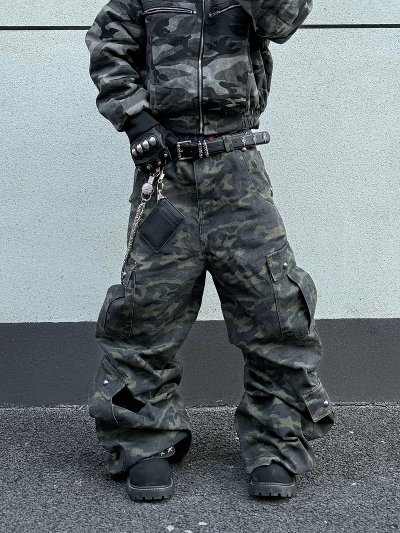 Front view of camo cargo pants styled with a studded belt, chain accessory, and loose fit