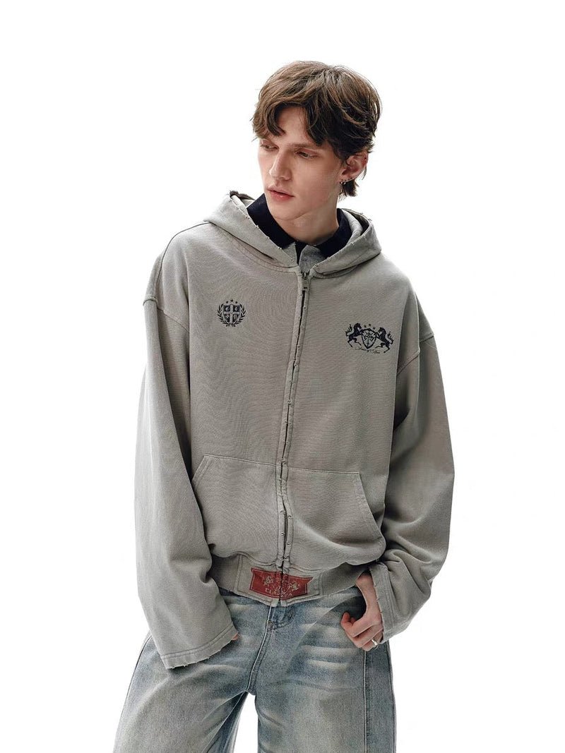Light gray washed zip hoodie worn by model, front angled view with crest prints