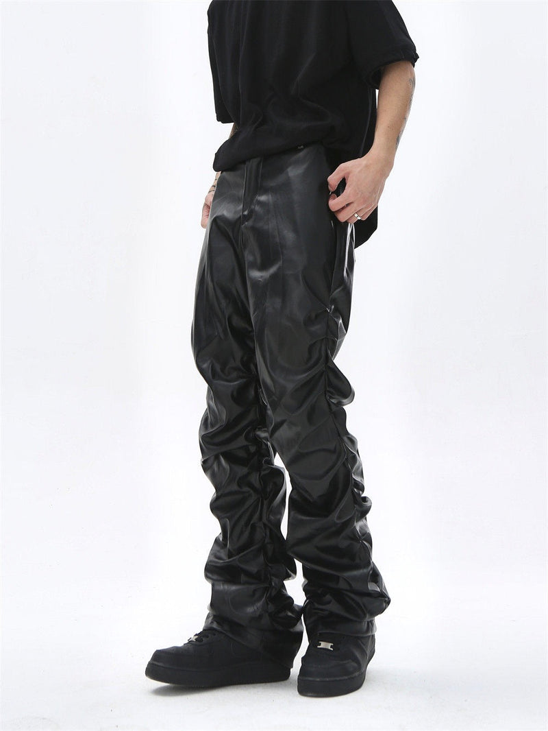 Black faux leather straight-leg pants worn from the side, with ruched texture along the leg