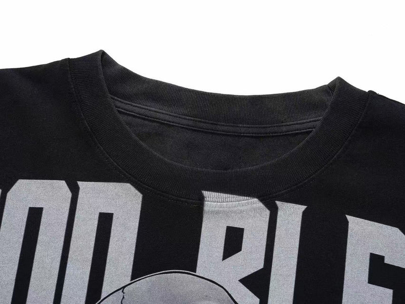Close-up of a black oversized graphic tee with bold white gothic lettering and a skeleton print on the chest
