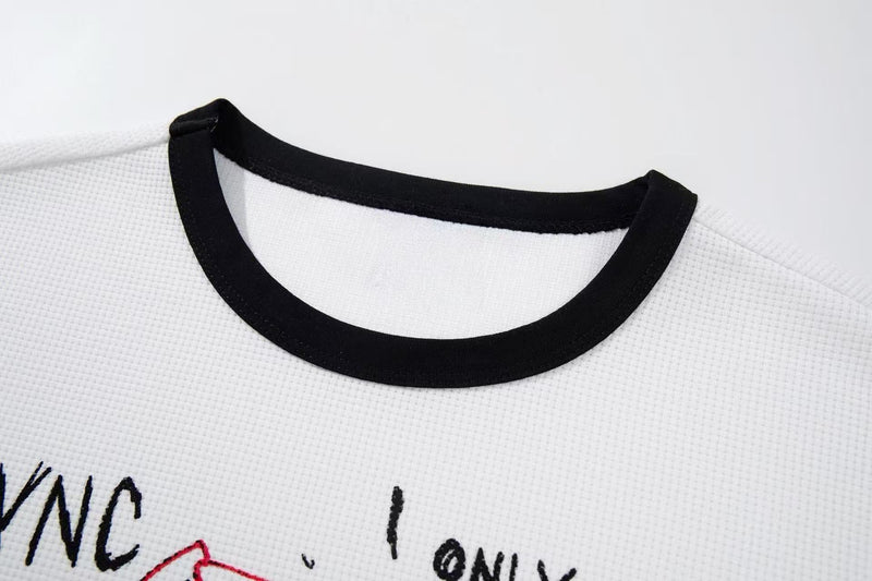 White ringer graphic tee with black collar and graffiti-style print on textured fabric close-up