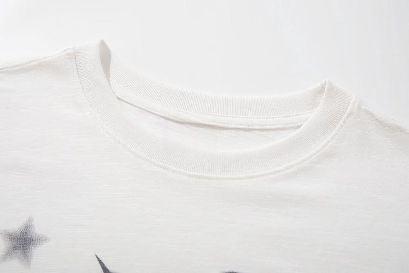 White crewneck graphic tee with a subtle star print and soft cotton texture, featuring a clean streetwear style