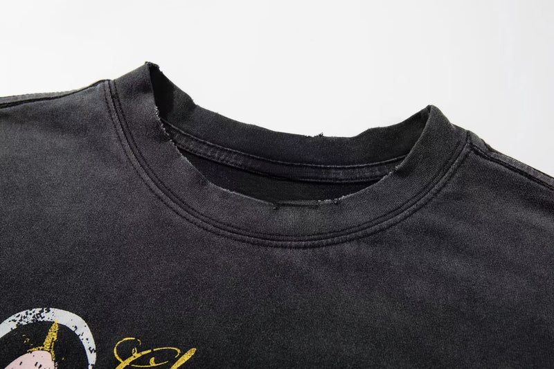 Close-up of a washed black graphic tee with distressed collar and street art style print in yellow and white