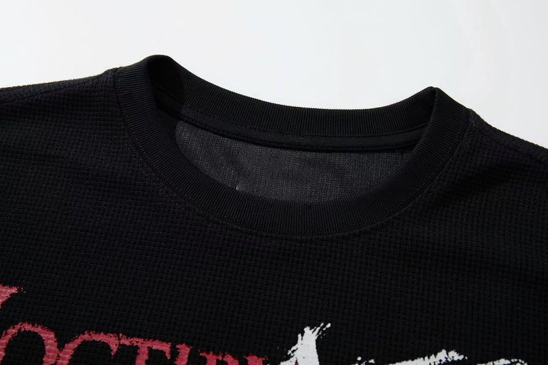 Close-up of a black cotton graphic tee with ribbed crew neckline and distressed pink-and-white print detail