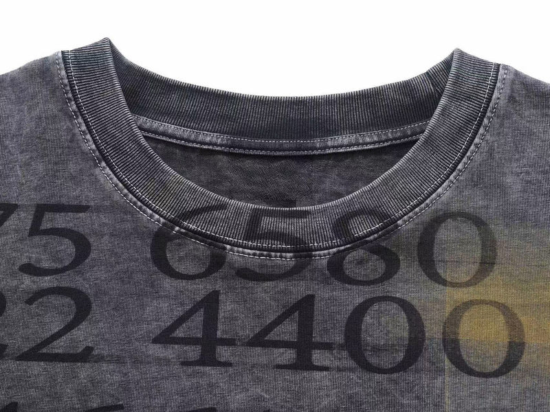 Close-up of a vintage wash graphic tee with oversized ribbed crew neckline and faded numeric print on charcoal fabric