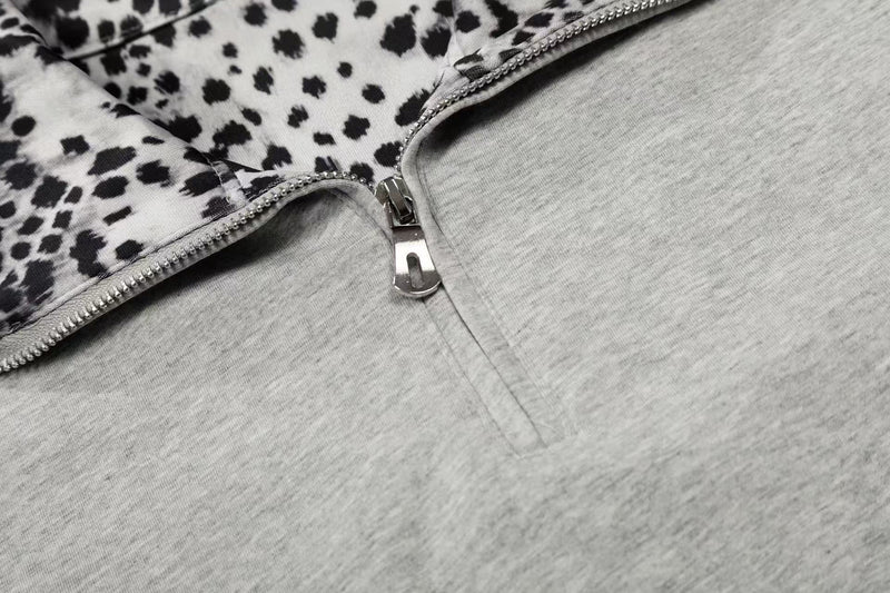 Close-up of a gray quarter-zip polo shirt with black leopard trim and silver zipper detail
