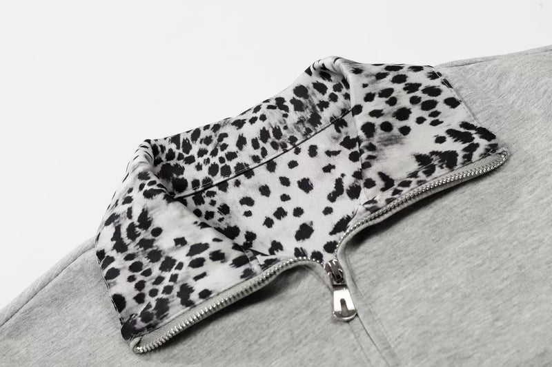 Close-up of a gray quarter-zip polo shirt with bold black leopard-print trim on the collar and placket