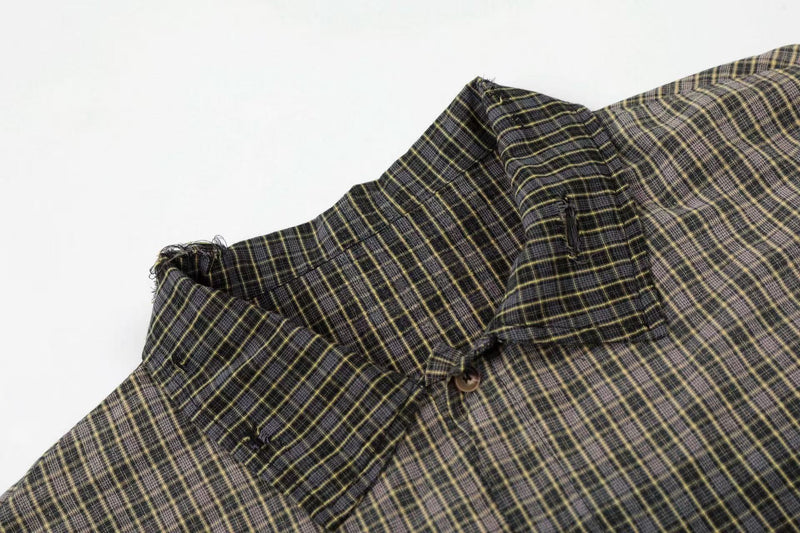 Distressed black and yellow plaid shirt with raw edges, shown close up on a white background