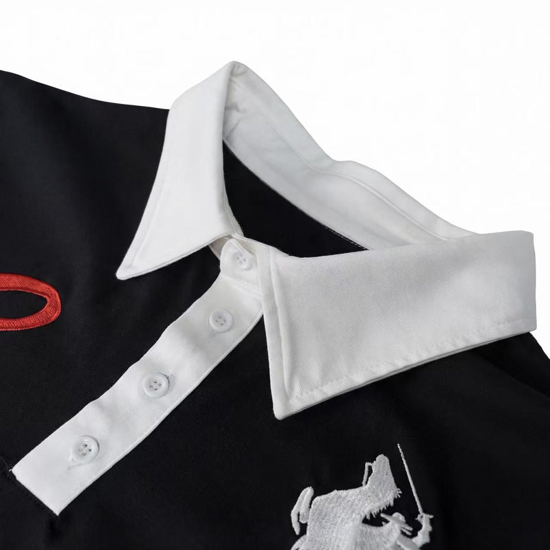 Black polo tee with white contrast collar and button placket, featuring embroidered knight graphic detail