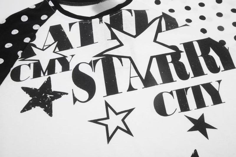 Close-up of starry city graphic on black and white polka dot raglan tee