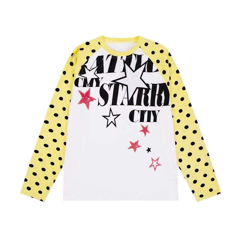 White raglan long sleeve tee with yellow polka dot sleeves and black and pink starry city graphic