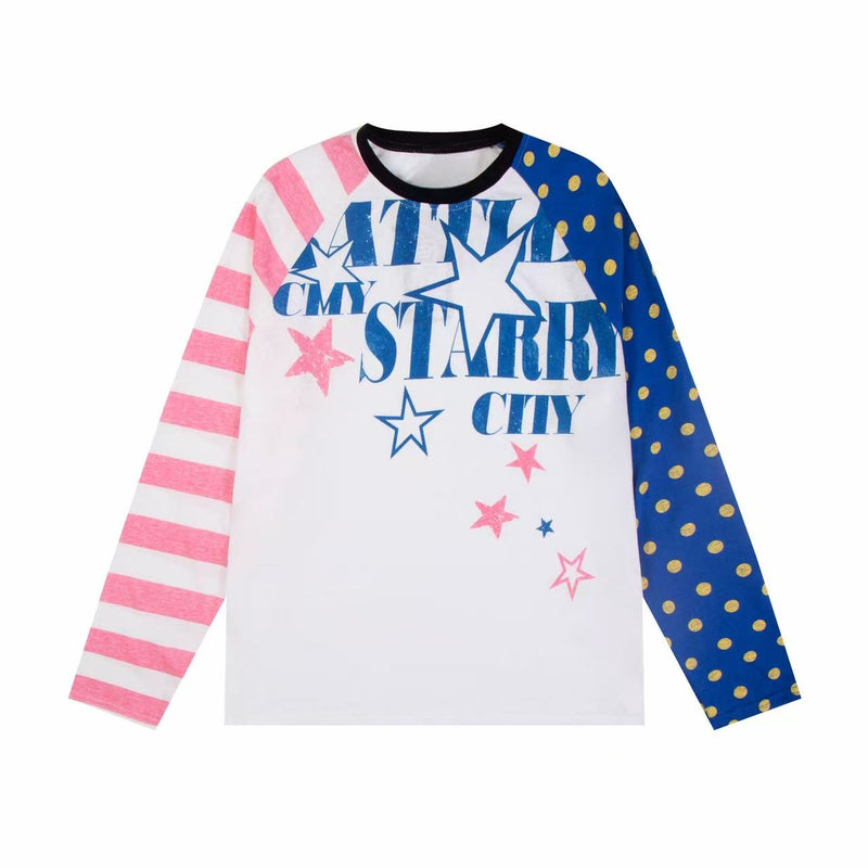 White raglan long sleeve tee with pink striped left sleeve, blue polka dot right sleeve, and blue starry city graphic