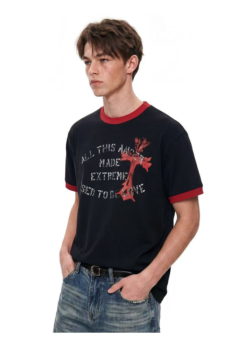 Black ringer T-shirt with red trim, distressed cross graphic, and faded slogan on a male model against a white background