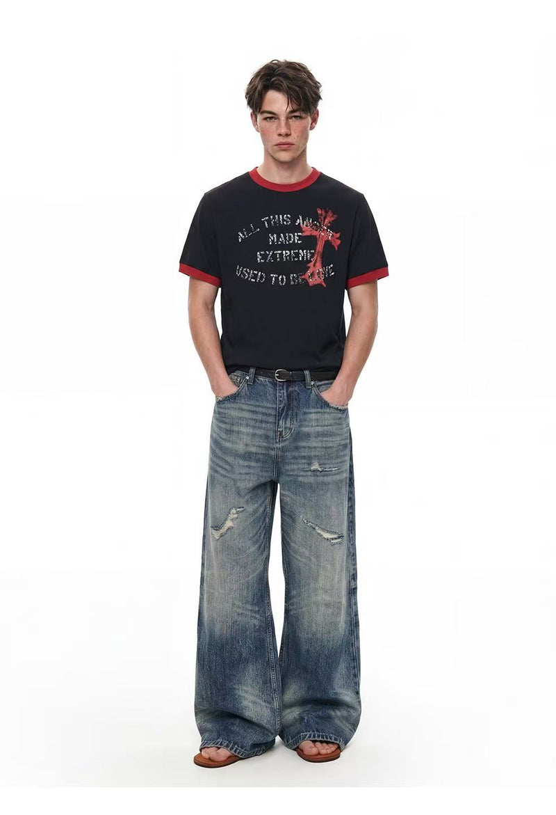 Black ringer t-shirt with red trim and distressed cross graphic, styled with loose faded wide-leg jeans