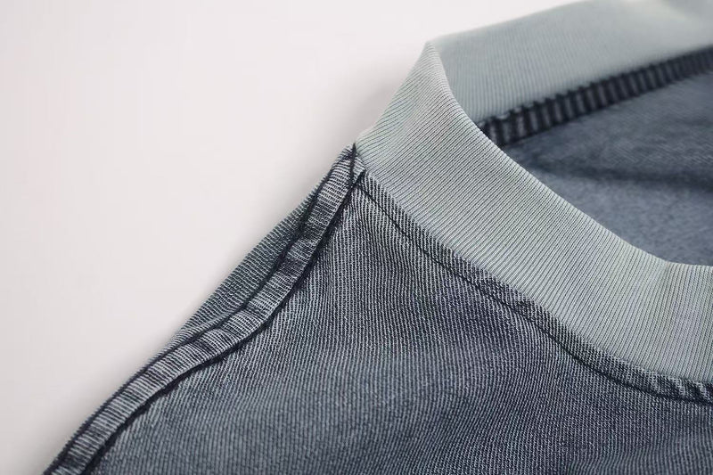Close-up of a vintage washed distressed T-shirt collar with visible stitching and faded denim blue fabric texture