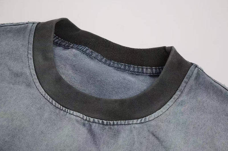 Close-up of a washed vintage graphic T-shirt with black ribbed crew neckline and faded blue denim-look fabric