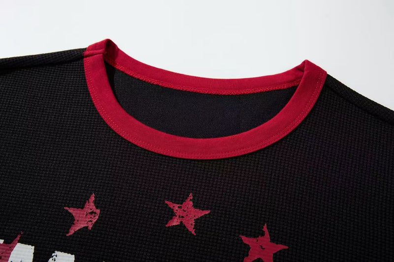 Black ringer T-shirt with red trim and distressed star graphic on a textured vintage tour design