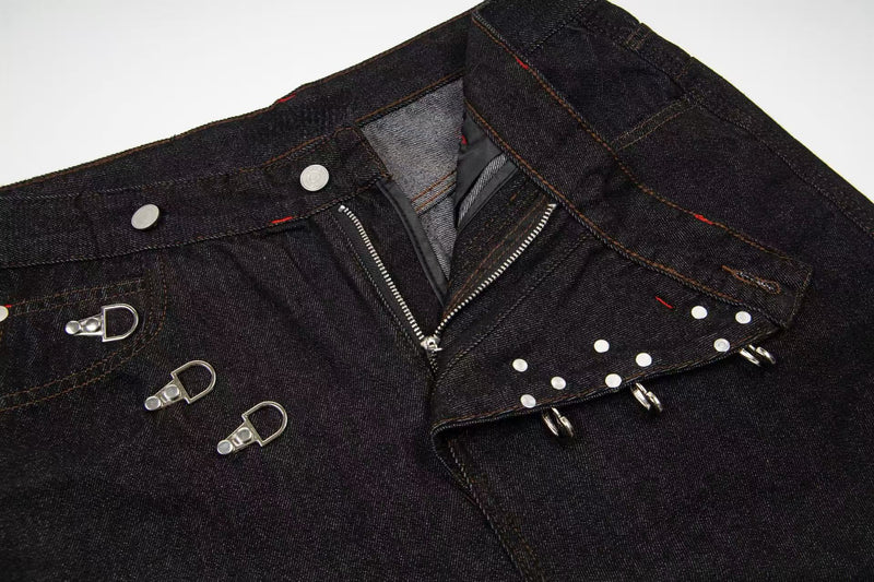 Close-up of waistband and front hook closures on dark wash denim pants with zipper fly
