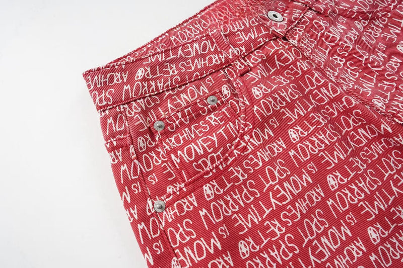 Close-up of red script print pants showing front waistband and button fly