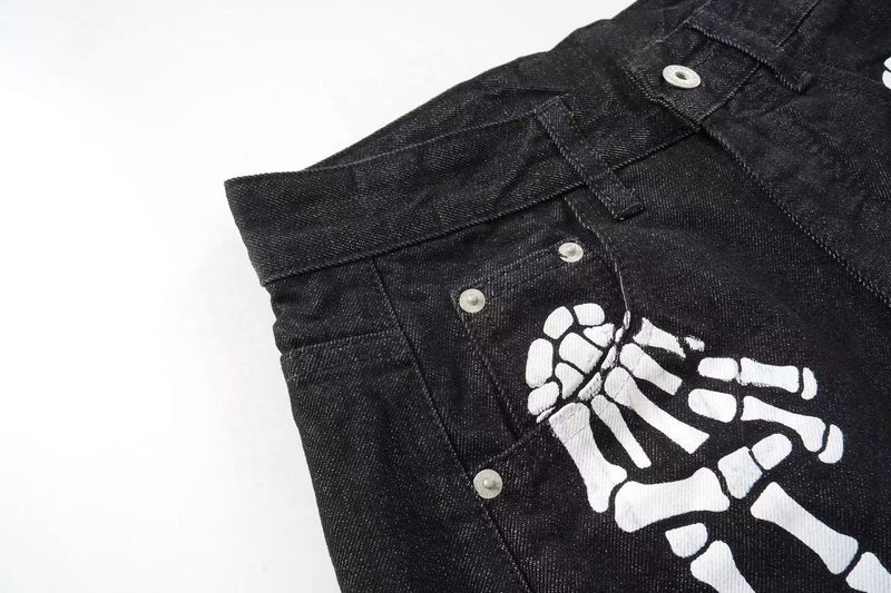 Close-up of black denim front pocket and white skeleton hand graphic