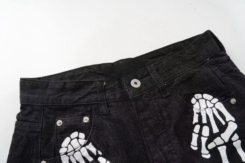 Close-up of black denim waistband with white skeleton hand print and metal rivets