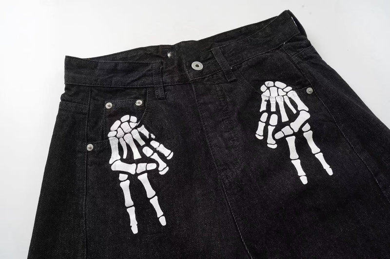 Front upper section of black denim pants with white skeleton hand prints near the pockets