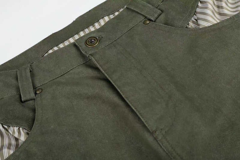 Close-up of army green pants front waistband and button with striped pocket lining