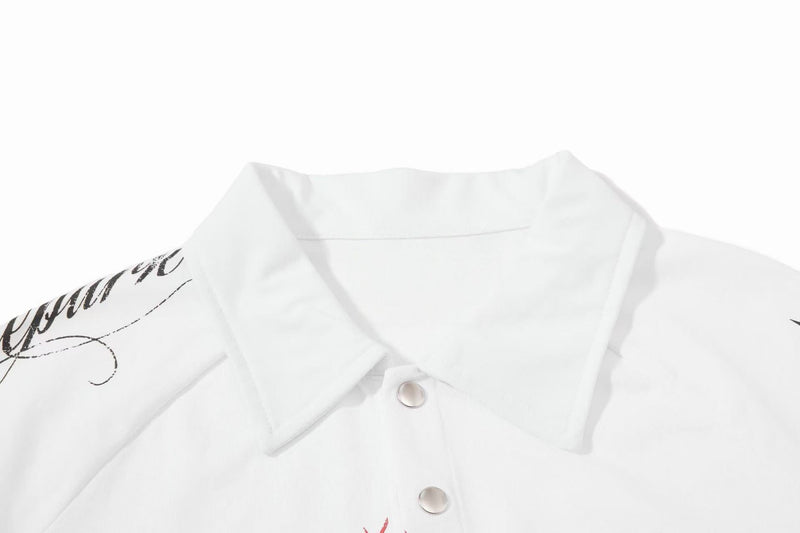 White distressed graphic polo shirt with black script print and snap buttons on a clean background
