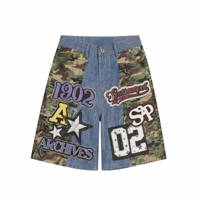 Front view of blue denim jorts with camouflage side panels and large varsity-style patch graphics