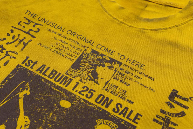 Yellow washed punk graphic tee with distressed retro print and bold vintage typography on the chest