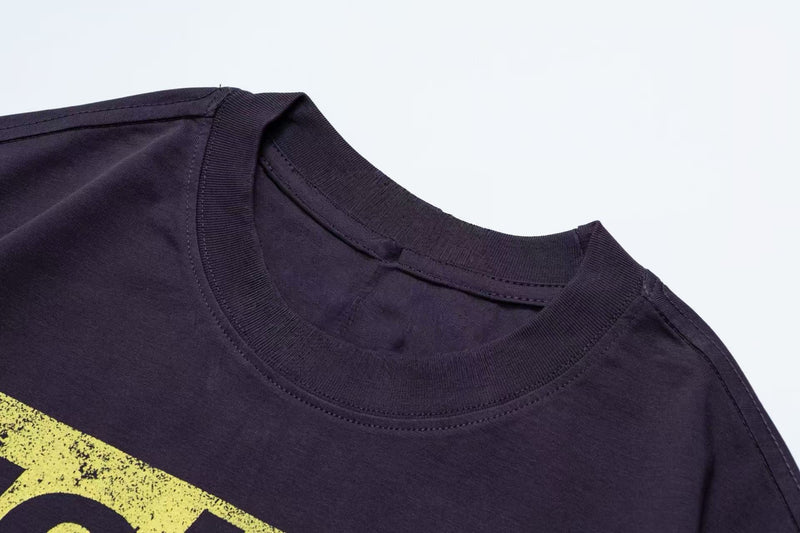 Dark oversized graphic tee with ribbed crewneck and yellow newspaper-style print on the chest