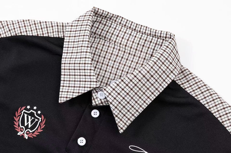 Black polo shirt with plaid panel collar, white buttons, and embroidered crest detail on the chest