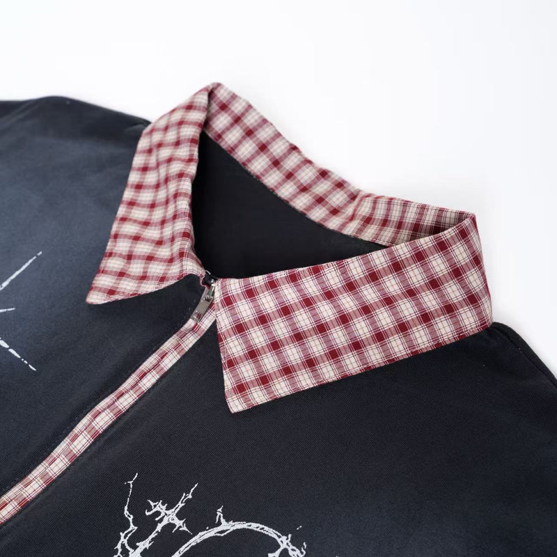 Black oversized polo shirt with red plaid collar and distressed white graphic print on the chest