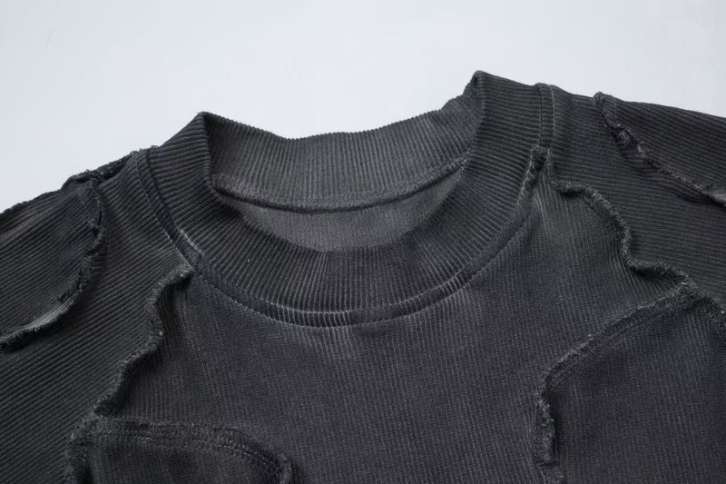Close-up of a black ribbed compression tee with raw seam detailing and deconstructed streetwear styling