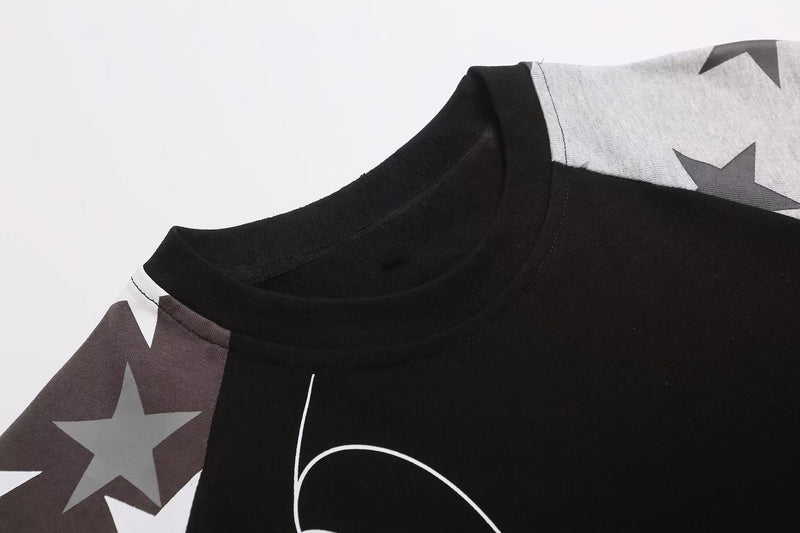 Black raglan tee with star print sleeves and gothic script detail on soft cotton fabric