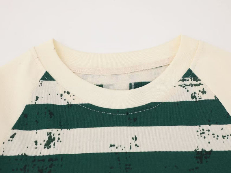 Close-up of cream tee collar with dark green stripes and raglan seam