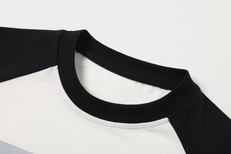 Close-up of black ribbed crew neckline on white raglan tee