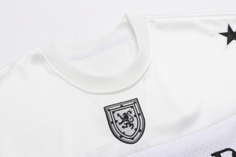 White varsity football jersey T-shirt with embroidered crest and black star detail, close-up streetwear design